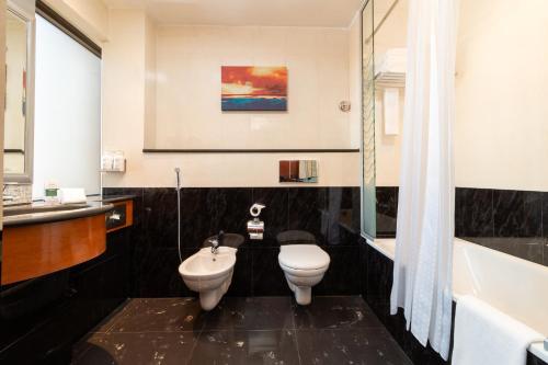 a bathroom with a toilet and a sink and a tub at Holiday Inn Kuwait by IHG in Kuwait
