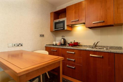 a kitchen with wooden cabinets and a wooden table at Holiday Inn Kuwait by IHG in Kuwait