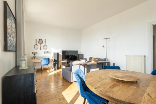 - un salon avec une table en bois et des chaises bleues dans l'établissement Superbe vue mer face à Nausicaa, à Boulogne-sur-Mer