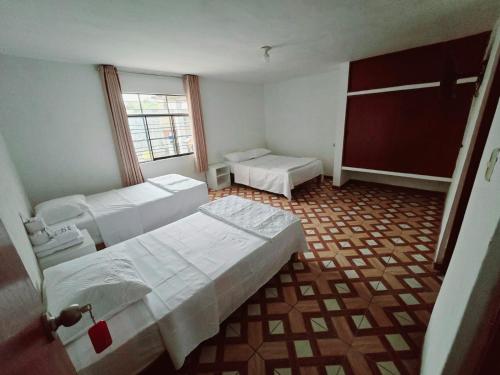a room with three beds and a window at Los Angeles Hotel in Huaral