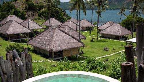 a group of huts with the ocean in the background at Bleu MATHIS Gili Asahan in Gili Asahan