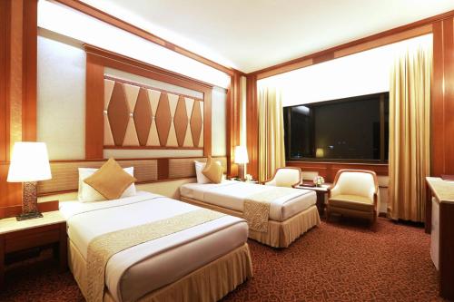 a hotel room with two beds and a flat screen tv at Asia Hotel Bangkok in Bangkok