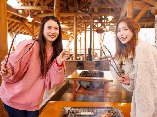 two women standing in front of a table with chopsticks at Hida-Osaka Fureai no Mori Bungalow in Gero