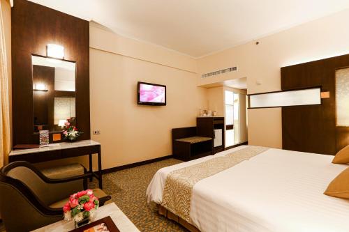 a hotel room with a bed and a chair at Asia Hotel Bangkok in Bangkok