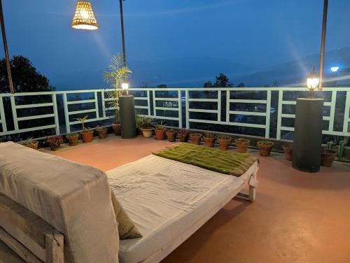 a bed on top of a balcony with plants at Indralok Hotel and Sky Garden in Deorāli