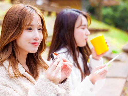 two girls are sitting down and eating food at Hida-Osaka Fureai no Mori Bungalow in Gero
