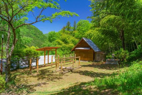 a cabin in the woods with a fence and trees at Hida-Osaka Fureai no Mori Bungalow in Gero