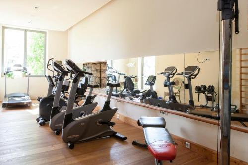 a gym with treadmills and ellipticals in front of a mirror at Hotel Bemelmans-Post in Collalbo