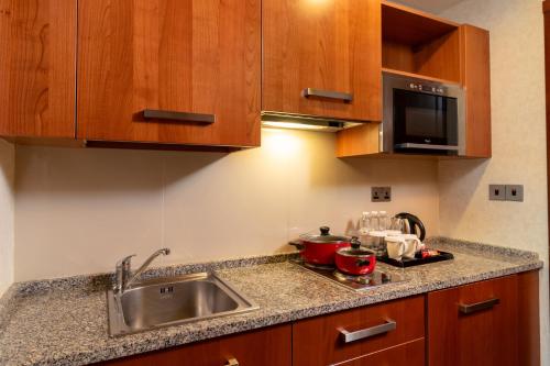 a kitchen with a sink and a microwave at Holiday Inn - Suites Kuwait Salmiya by IHG in Kuwait