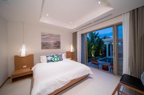 a bedroom with a bed and a large window at Modern 3BR Pool Villa T-Breeze in Laguna Phuket