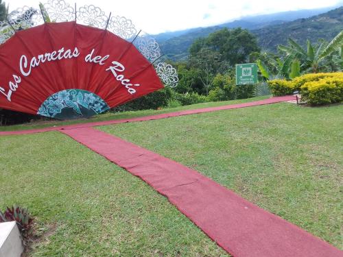 a red umbrella sitting on top of a grass field at Las Carretas Del Rocio in Palestina