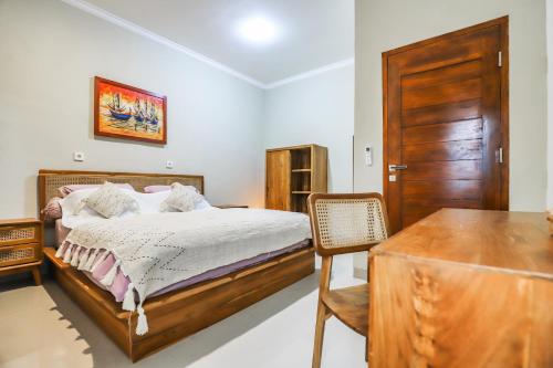 a bedroom with a bed and a wooden door at Unwind in 2BDR Ubud Villa Oceania - Huge Pool & Lawn in Ubud