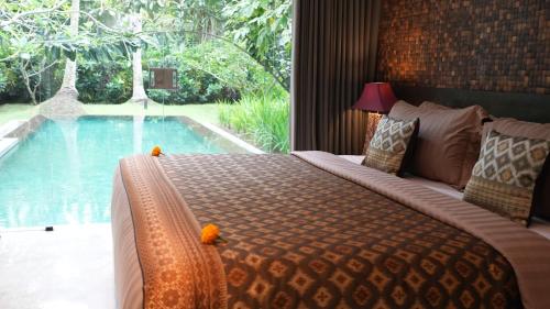 a bedroom with a bed and a swimming pool at Kelapa Retreat & Spa in Pulukan