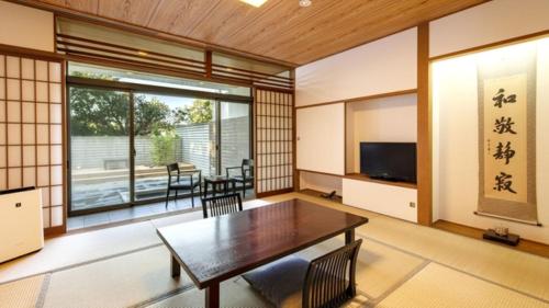 a living room with a table and chairs and a television at Kurhouse Shirahama in Shirahama