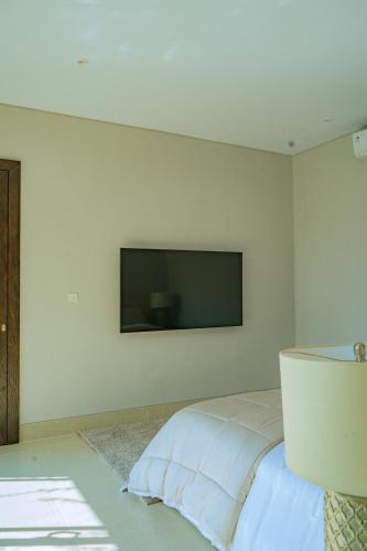 a bedroom with a flat screen tv on the wall at Villa Espresso Ubud in Sukawati
