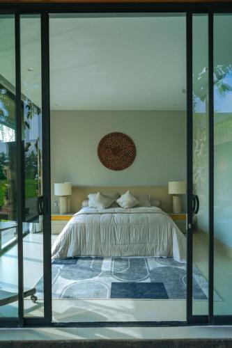 a bedroom with a large bed with glass doors at Villa Espresso Ubud in Sukawati