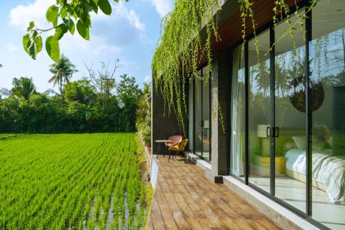 a room with glass walls and a view of a field at Villa Espresso Ubud in Sukawati