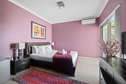 a bedroom with purple walls and a bed with a television at Waterfront Ensuite Queen Room - Luxury & Comfort Place in Caringbah South in Lilli Pilli