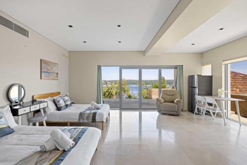 a large room with two beds and a balcony at Waterfront Studio Room for Four - Breathtaking Coastal Escape at Caringbah South in Lilli Pilli