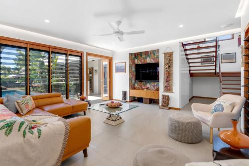 a living room with a couch and chairs and a tv at The Peony Isle - Luxe Lakeside Haven with Pool & Spa in Trinity Beach