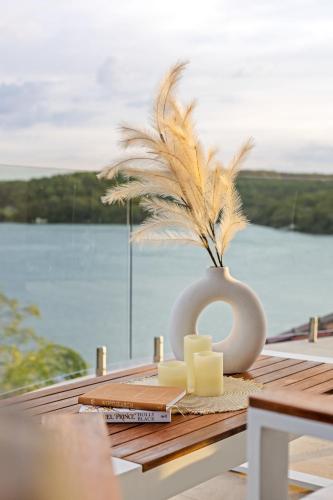 a table with a vase with two candles and a plant at Tranquil Retreat at Caringbah South - Waterfront Ensuite King Room with Spectacular Views in Lilli Pilli