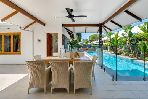 a dining room with a table and chairs and a swimming pool at The Peony Isle - Luxe Lakeside Haven with Pool & Spa in Trinity Beach