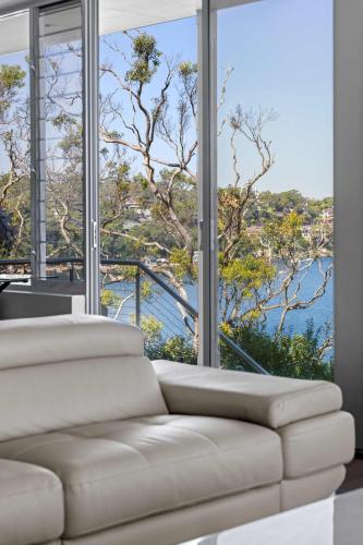 a white couch in a room with a large window at Tranquil Retreat at Caringbah South - Waterfront Ensuite King Room with Spectacular Views in Lilli Pilli