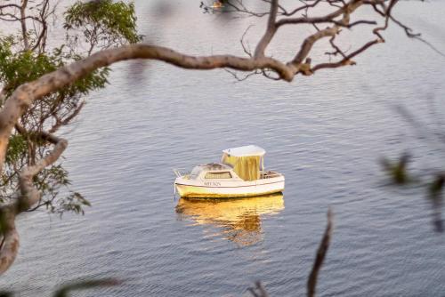 a small boat sitting in the middle of the water at Tranquil Retreat at Caringbah South - Waterfront Ensuite King Room with Spectacular Views in Lilli Pilli