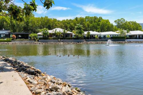 a pond with ducks in the water with buildings in the background at The Peony Isle - Luxe Lakeside Haven with Pool & Spa in Trinity Beach