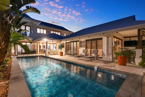 a house with a swimming pool in front of a house at The Peony Isle - Luxe Lakeside Haven with Pool & Spa in Trinity Beach