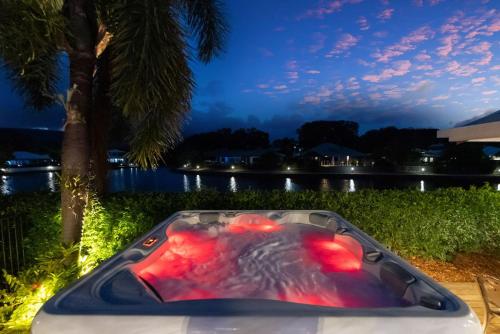 a bath tub sitting in the grass next to a river at The Peony Isle - Luxe Lakeside Haven with Pool & Spa in Trinity Beach