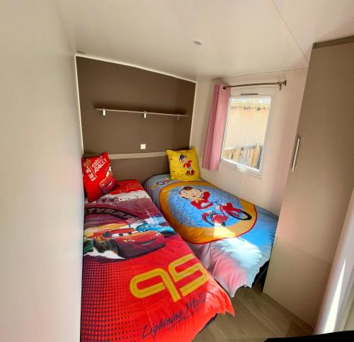 deux lits dans une petite pièce avec une fenêtre dans l'établissement Vias Mobil home 6-8 pers tout confort climatisé, à Vias