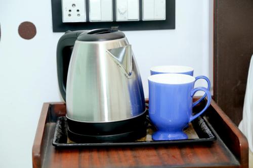 a coffee pot and a cup on a table at JMC Hotel RK Inn in Dakan Kotra