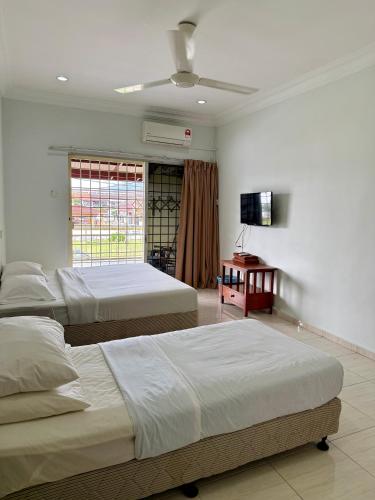 two beds in a room with a television and a room with two beds at Eco Stay Guesthouse in Kuantan
