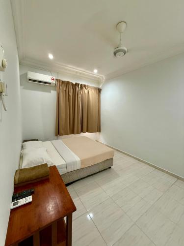 a bedroom with a bed and a table in it at Eco Stay Guesthouse in Kuantan