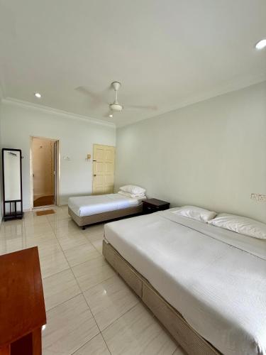 a bedroom with two beds and a table in it at Eco Stay Guesthouse in Kuantan