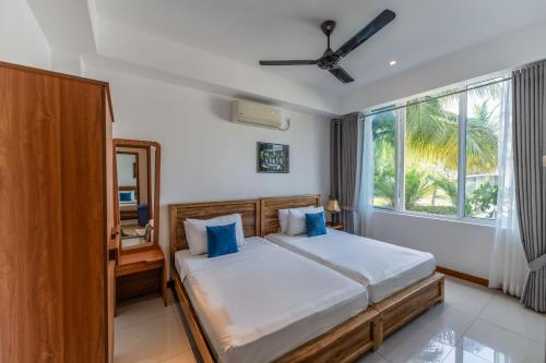 a bedroom with a bed with blue pillows and a window at Oceanfront Condominium - Nilaveli in Nilaveli