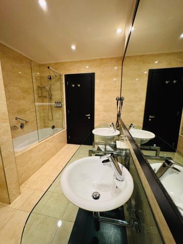 a bathroom with two sinks and a shower at Hotel Rivo Timisoara in Timişoara