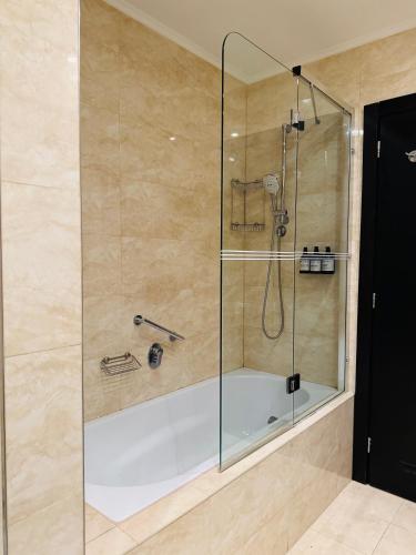 a shower with a glass door and a tub at Hotel Rivo Timisoara in Timişoara