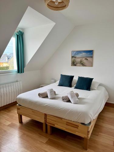a bedroom with a large white bed with blue pillows at Charmante maison familiale in Ouistreham