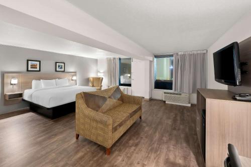 a hotel room with a bed and a television at Clarion Inn & Suites and Convention Center in Kearney