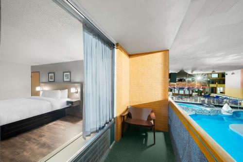 a hotel room with a bed and a swimming pool at Clarion Inn & Suites and Convention Center in Kearney