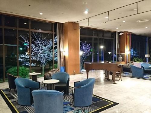 a lobby with a piano and chairs and tables at Hotel New Otani Saga in Saga