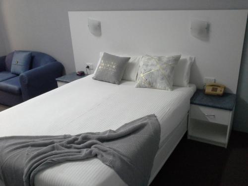 a bedroom with a bed and a blue chair at Hideaway Motor Inn in Armidale