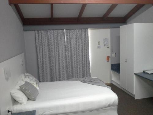 a bedroom with a white bed and a window at Hideaway Motor Inn in Armidale