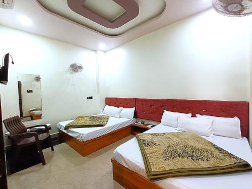 a hotel room with two beds and a chair at Hotel Shreem in Ujjain