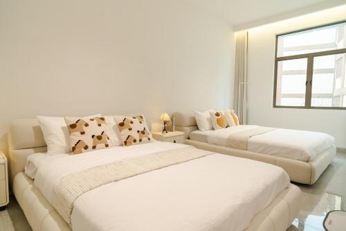 a white bedroom with two beds and a window at Georgetown Bright & Kid-Friendly KTV 3BR 15pax C in George Town