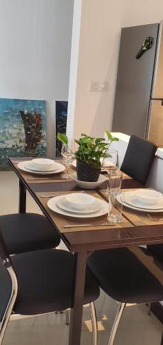 a wooden table with plates and glasses and a plant on it at Luxury 32nd Floor 2 Bed-2 Bath Apartment with Pool, Harbour & Lotus Tower views in Colombo