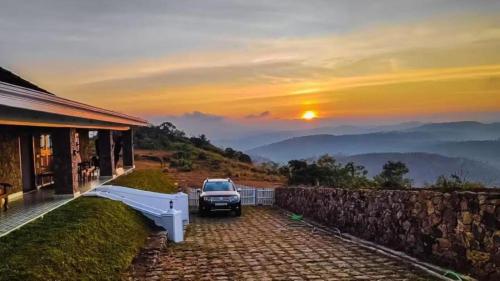 a car parked in front of a house with the sunset at Anudhyana Premium Private Stone Villa Vagamon by VOYE HOMES in Vagamon