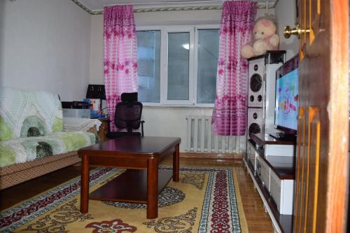 a living room with a table and a tv in it at Camel Track Guesthouse and Tour Operator LLC in Ulaanbaatar